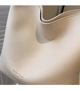 Détail du sac seau en cuir grainé blanc crème avec logo embossé et texture fine