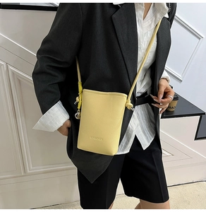 Dettaglio della borsa a secchiello gialla in pelle con logo Summoment e decorazione laterale