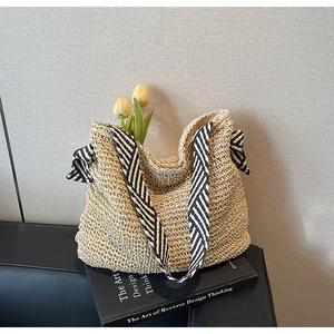 Detail of straw woven tote with striped silk scarf and tulips on a designer book