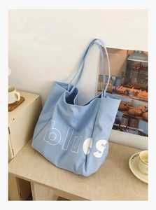 Détail du sac fourre-tout en toile bleu clair avec lettres sur table en bois