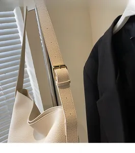 Gros plan détaillé du sac seau en cuir beige avec boucle métallique dorée chic