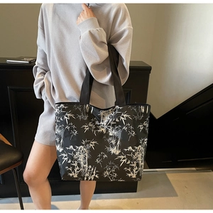 Close-up of black canvas tote bag featuring artistic white bamboo prints and wide straps