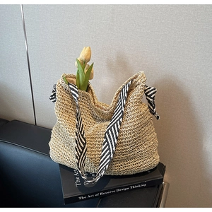 Detail of straw woven tote bag featuring striped silk scarf handles and tulip decoration