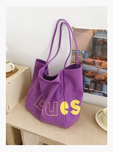 Détail du sac cabas en toile violette avec lettres Blues jaunes dans un décor minimaliste