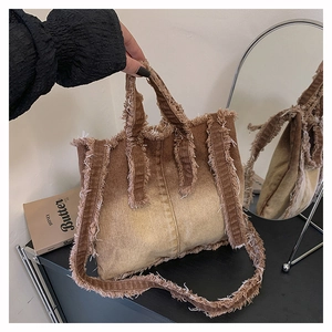 Vue détaillée du sac cabas en jean vintage avec dégradé de couleurs et bords effilochés