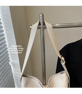Détail de la bandoulière large réglable avec boucle argentée sur un sac en cuir beige