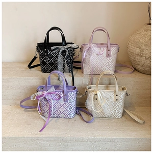 Detail of four colorful bucket bags with geometric patterns and lace bows on display