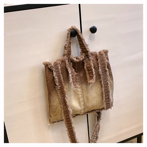 Détail du sac cabas en jean vintage dégradé avec bords effilochés et texture délavée