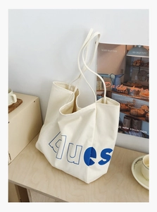 Détail d'un sac cabas en toile avec lettrage dues bleu sur une table en bois vintage