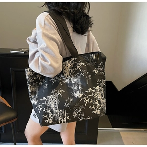 Detail of a large black canvas tote bag featuring white bamboo prints and wide shoulder strap