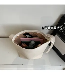Intérieur spacieux du sac seau beige contenant une tablette, un carnet et un parapluie