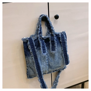 Détail du sac cabas en jean bleu avec bords effilochés et bandoulière réglable