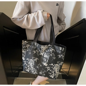 Detail of large black canvas tote bag featuring white bamboo leaf print and wide straps