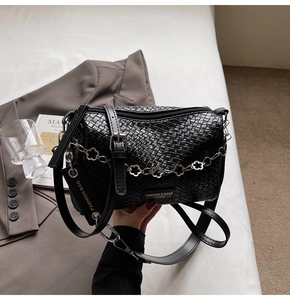 Detail of black woven crossbody bag with floral chain and fashion leather tag