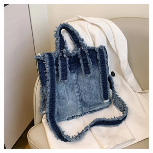 Détail des bords effilochés et texture denim délavé d'un sac cabas rétro chic