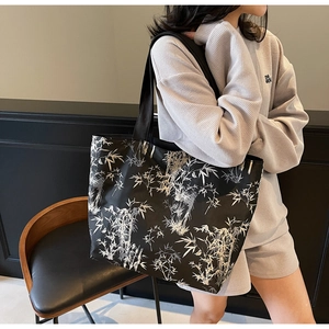 Detail of bamboo leaf print on large black canvas tote bag with wide shoulder strap