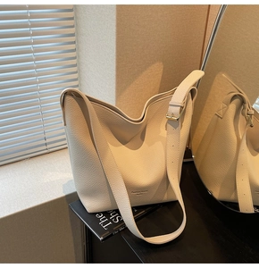 Détail du sac seau beige en cuir grainé avec bandoulière à boucle dorée ajustable