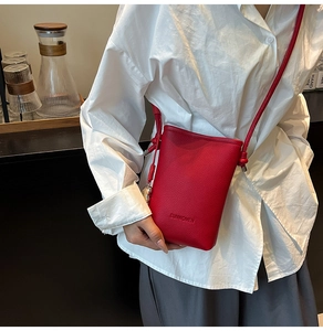 Dettaglio della borsa a secchiello rossa in pelle martellata con logo SUNWOMEN in rilievo