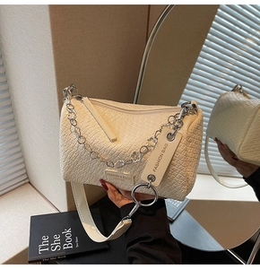 Detail of woven texture on beige crossbody pillow bag with silver floral chain and strap