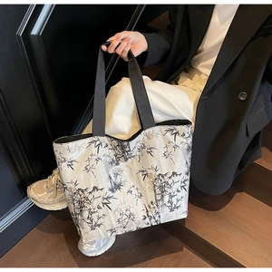 Close-up of a large canvas tote bag featuring an elegant black bamboo ink print design