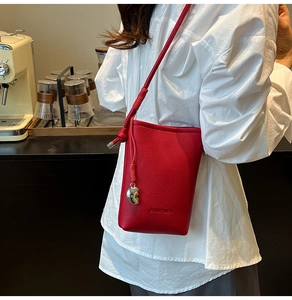 Dettaglio della borsa a tracolla rossa in pelle martellata con logo SUNWOMEN e ciondolo