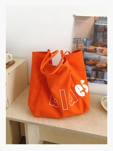 Détail du sac fourre-tout orange en toile montrant l'imprimé Alaes et la bandoulière