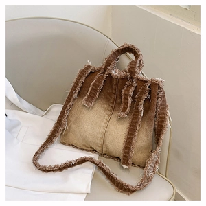 Détail du sac cabas en jean marron dégradé avec bords effilochés et doubles anses robustes