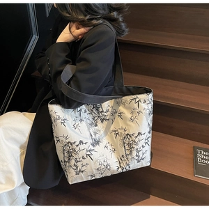 Detail of canvas tote bag featuring black and white bamboo leaf print with shoulder strap