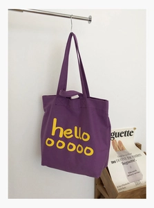 Detail van paarse canvas tote tas met gele letters en dubbele handgrepen