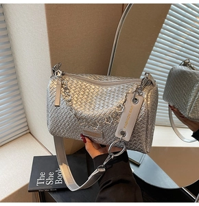 Detail of silver woven cylinder bag with floral chain strap and wide shoulder belt