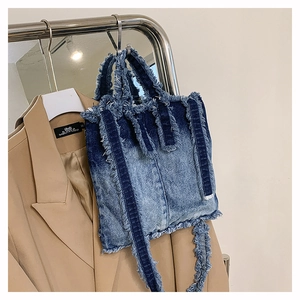 Détail du sac cabas en jean avec bords effilochés et bandoulière amovible réglable