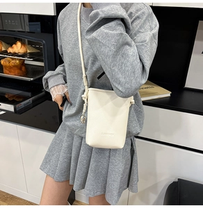 Dettaglio mini borsa a secchiello in pelle beige con ciondolo a cuore e logo SUNWOMEN