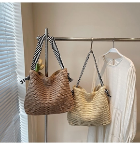 Detail of woven straw tote bags with striped straps and bow accents in sunlit setting