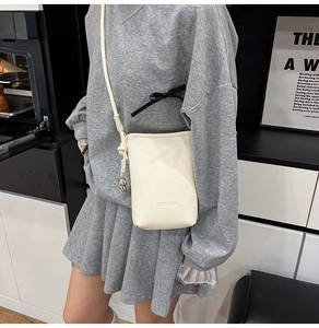 Dettaglio della borsa a secchiello beige con trama in pelle martellata e logo inciso