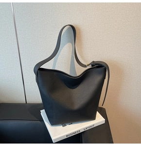 Gros plan sur la texture du cuir noir grainé et le logo discret embossé du sac seau chic