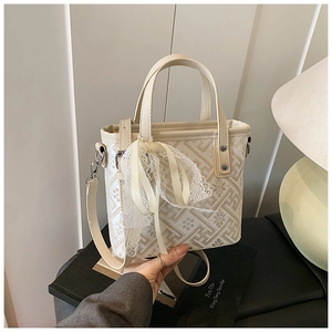 Detail of off-white crossbody bag featuring geometric texture and lace bow ornament