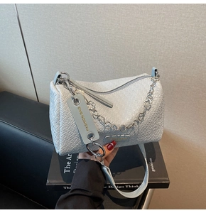 Detailed close-up of light blue woven texture faux leather bag with chunky silver chain