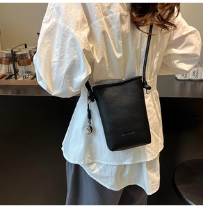 Dettaglio mini borsa a secchiello cilindrica nera in pelle con ciondolo a cuore