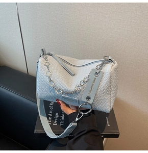 Detail of light blue woven barrel bag with floral silver chain and leather strap