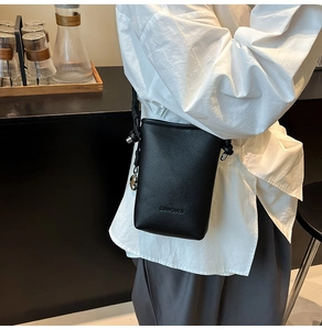 Dettaglio della mini borsa a tracolla in pelle nera testurizzata con logo in rilievo