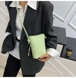 Dettaglio mini borsa a tracolla verde chiaro con trama in pelle e ciondolo argento