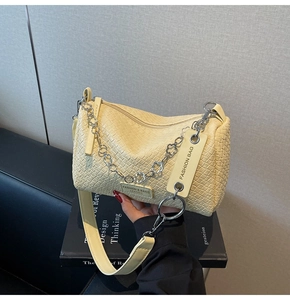 Detail of light yellow woven pillow bag with floral chain and adjustable strap
