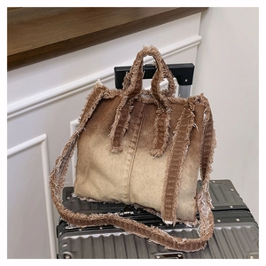 Détail des bords effilochés et du denim dégradé marron sur un grand sac cabas