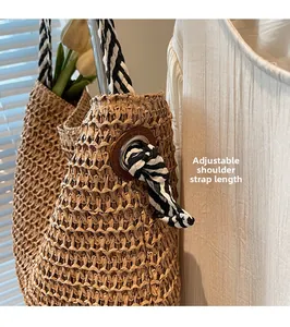 Detail of handwoven straw tote with adjustable black and white striped rope shoulder strap
