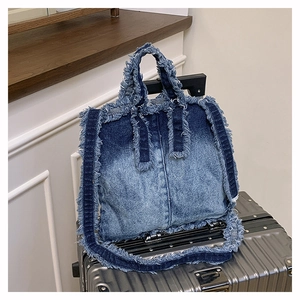 Détail du sac en jean avec bords effilochés et texture délavée sur une valise