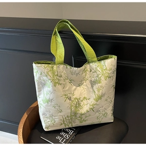 Detail of large canvas tote bag featuring green bamboo prints and green fabric handles