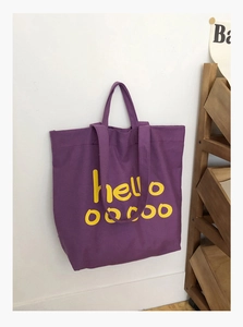 Detail van paarse canvas draagtas met gele 'hello' print en ronde stippen versiering