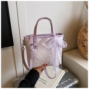 Detail of lavender bucket bag with geometric patterns and a white lace bow accent