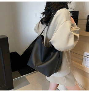 Vue détaillée du sac seau noir en cuir grainé avec large bandoulière et logo embossé