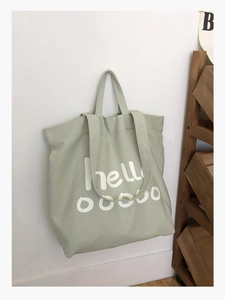 Detailweergave van saliegroene canvas draagtas met witte handgeschreven tekstprint